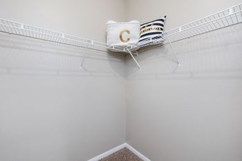 A spacious closet with a wire basket and a pillow with the letter c on it